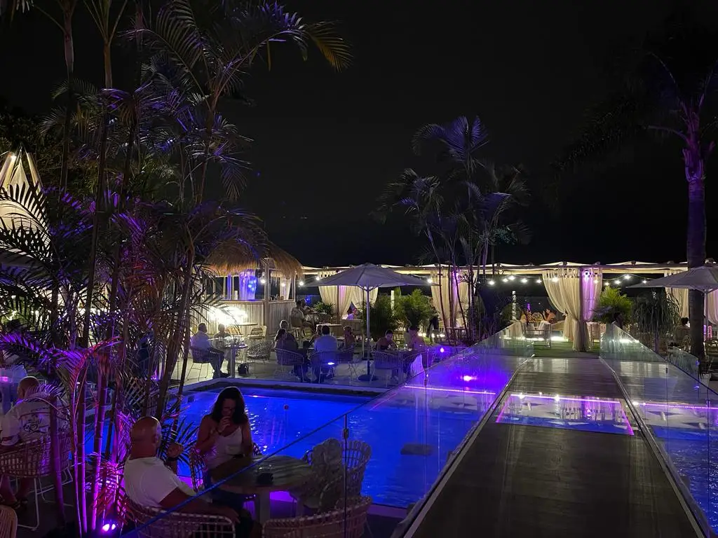 Garten und beleuchteter Pool bei Tito’s Beach am Abend